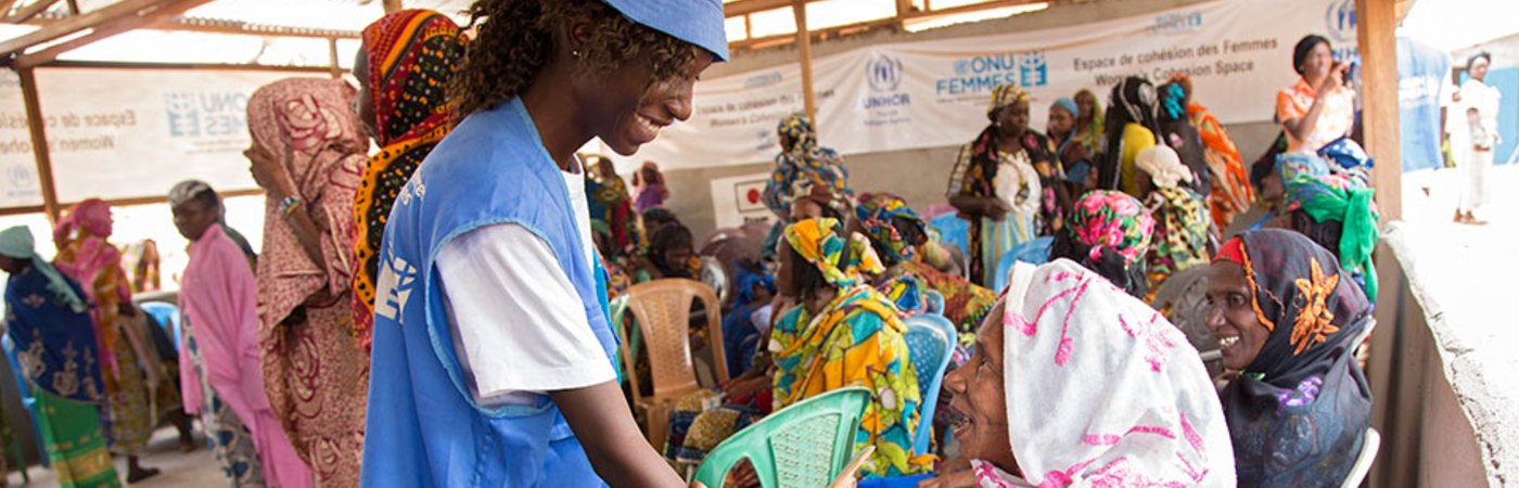Female United Nations worker smiling and shaking hands with a woman.