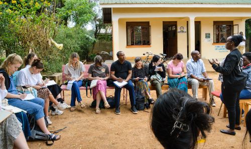 A group of students writing in notebooks during a trip to Uganda.